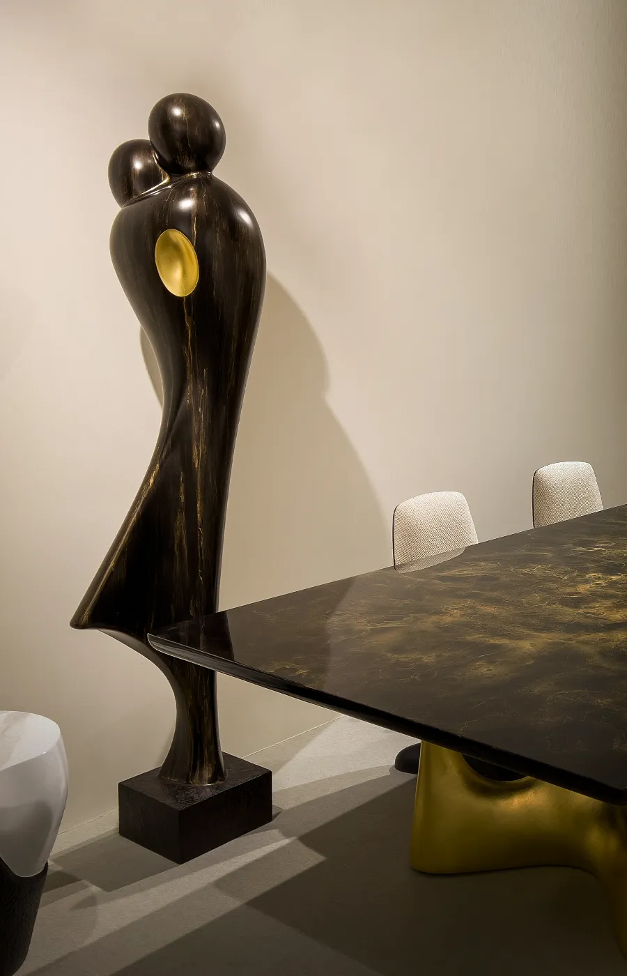 Zona de refeição com escultura Abraço em acabamento cor bronze e dourado junto a mesa Invicta