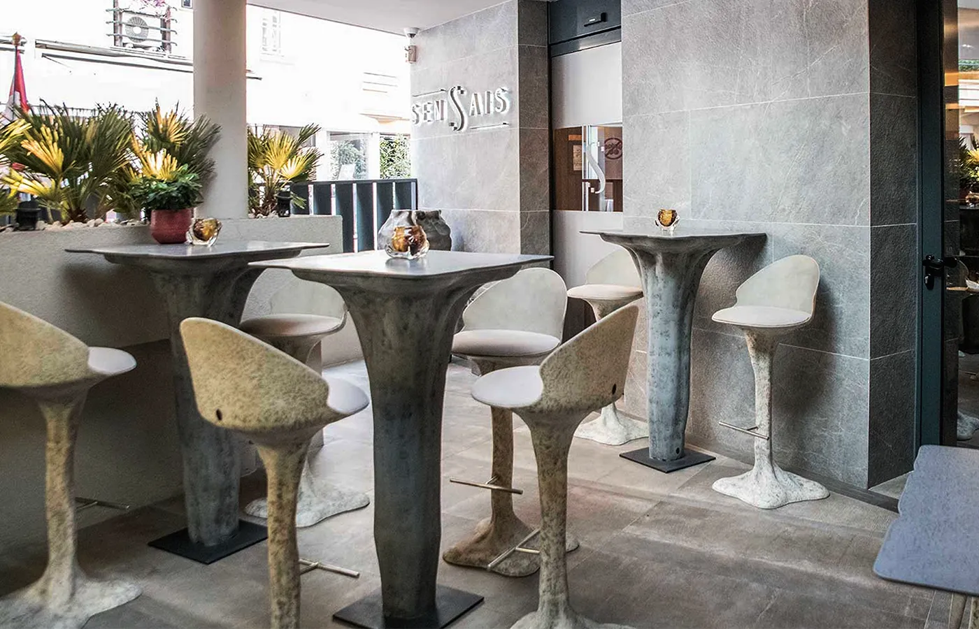 Bar lounge exterior com vários bancos bar Flora, com estrutura em fibra de vidro natural e almofada cinza
