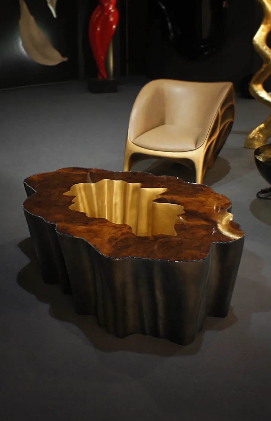 Gaia coffee table in brass color with walnut root top in showroom setting