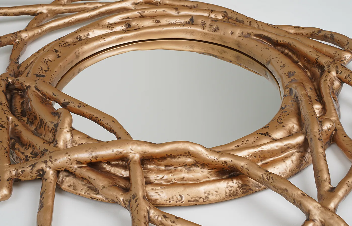 Espelho Nest em acabamento ouro envelhecido sobre textura orgânica