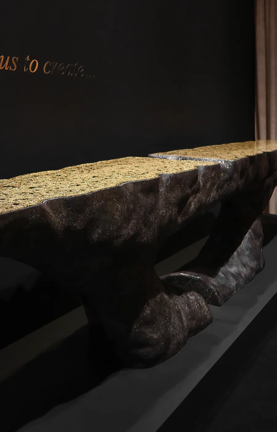 Ambiente de showroom com consola Pompeia em acabamento/textura vulcânica e tampo em folha de ouro texturada