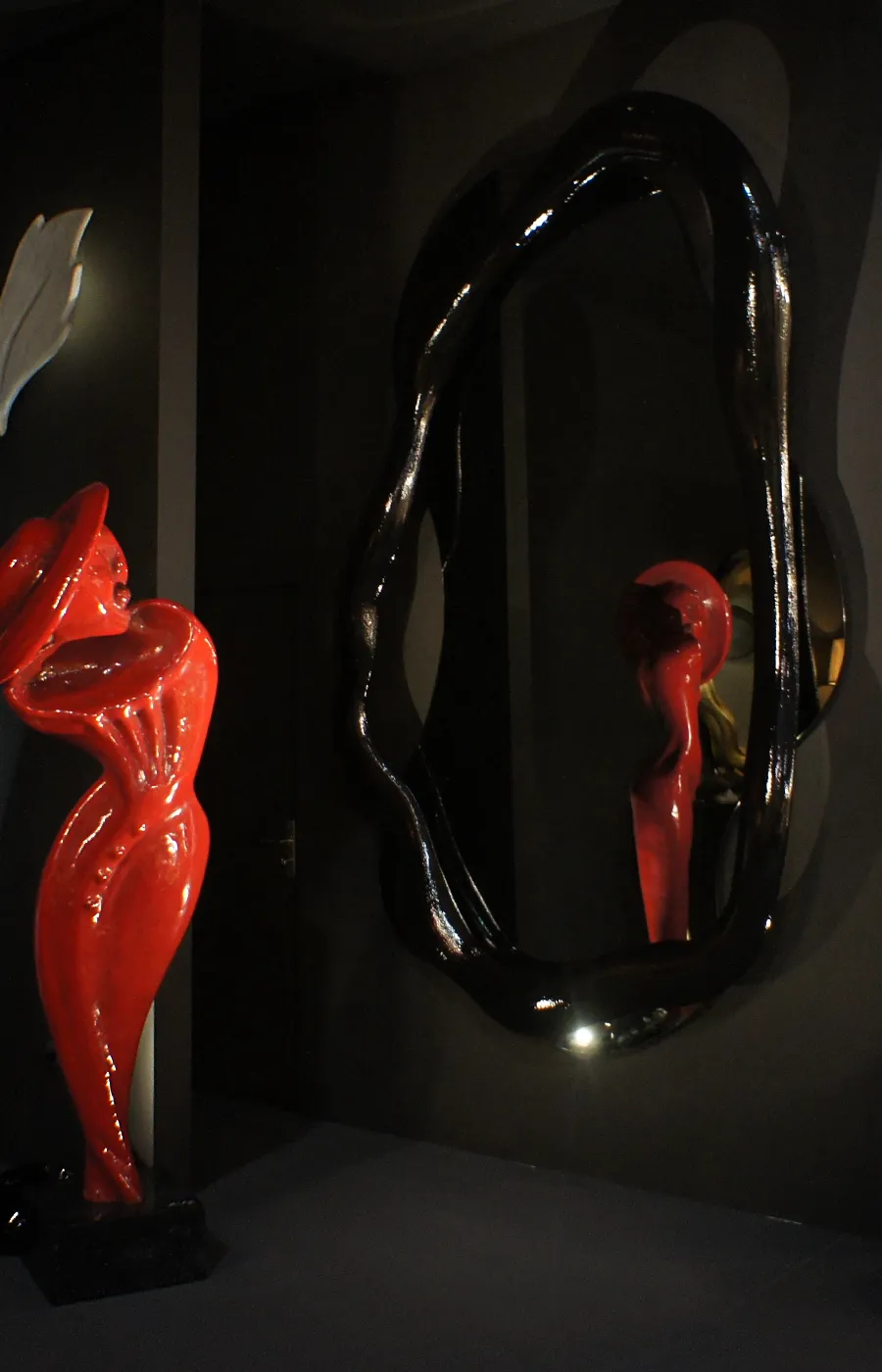 Showroom setting with large Twisted mirror in high-gloss textured black alongside the Musa sculpture